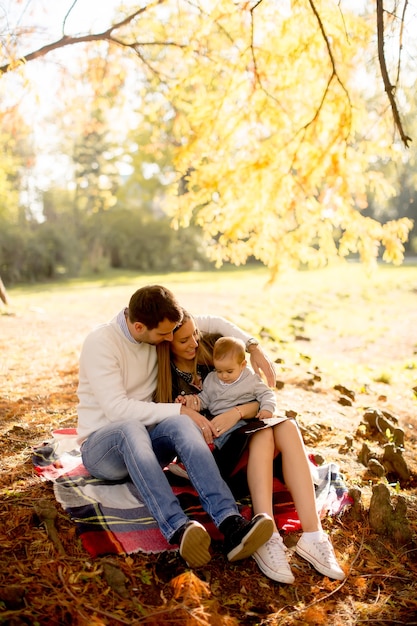 Jeune famille assis sur le sol en automne parc