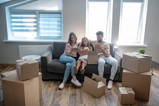 Jeune famille assise sur le canapé et regardant des photographies