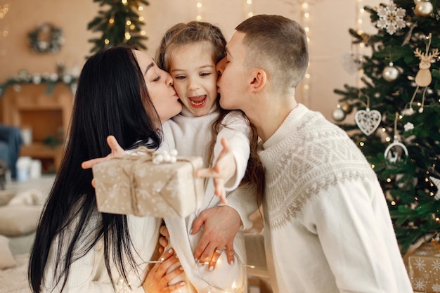 Jeune famille assise près du sapin de Noël et célébrant ensemble