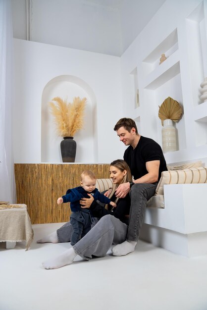 Une jeune famille assise sur le sol dans le salon et jouant avec son petit fils.