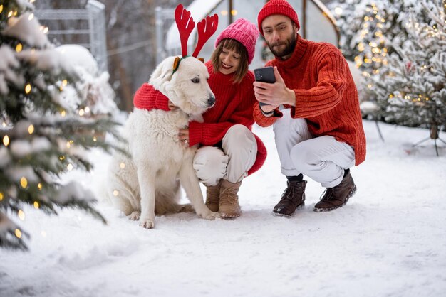 Une jeune famille avec un chien célèbre les vacances d'hiver