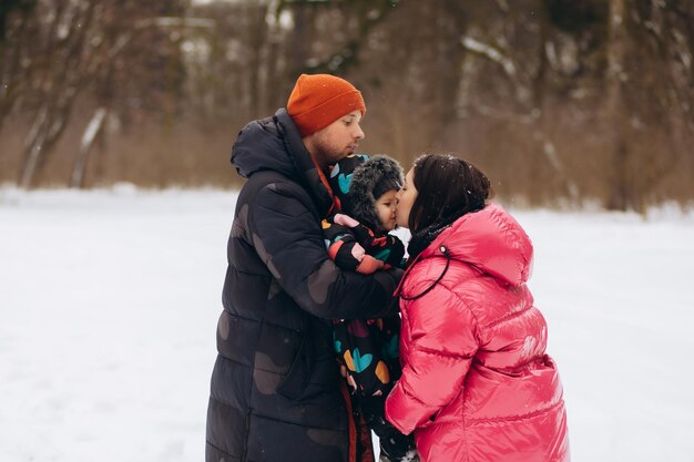 Jeune famille contemporaine composée d'un père, d'une mère et d'un fils profitant d'une journée d'hiver dans un parc tandis qu'un afro-américain portant un petit garçon sur les épaules Photo de haute qualité