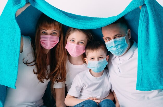 Jeune famille dans des masques médicaux pendant la quarantaine à domicile.