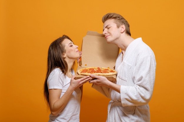 Jeune famille dans des vêtements avec pizza italienne