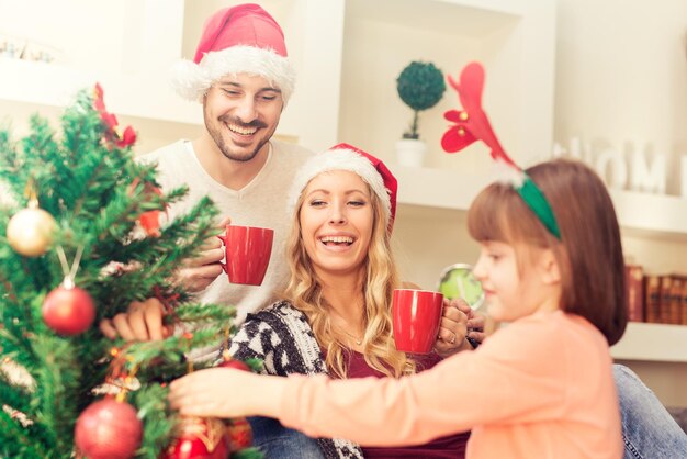 Jeune famille décorer un sapin de Noël