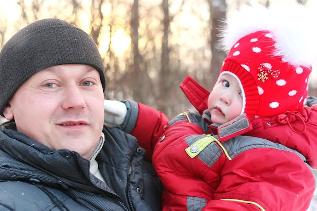 Jeune famille avec enfants en promenade dans le parc en hiver