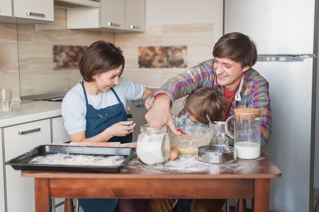 jeune famille espiègle préparant des biscuits ensemble à la cuisine