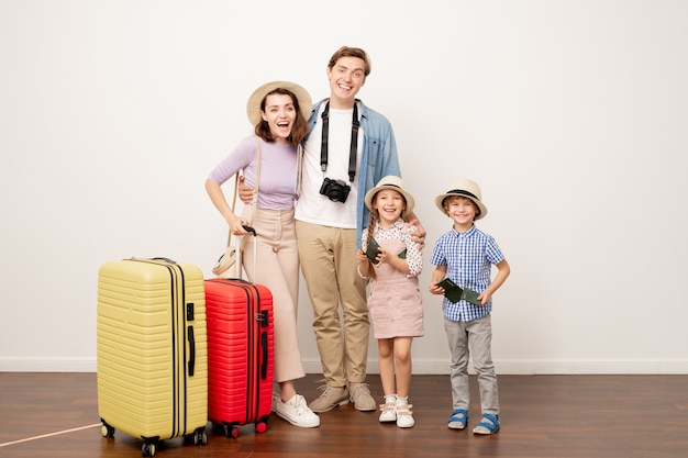 Jeune famille excitée de deux parents et leurs enfants mignons dans des vêtements décontractés avec des valises prêtes pour le voyage