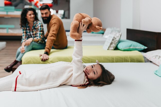 Jeune famille heureuse achetant un nouveau lit et matelas dans un grand magasin de meubles