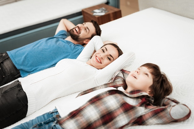 Jeune famille heureuse allongée sur un matelas en magasin