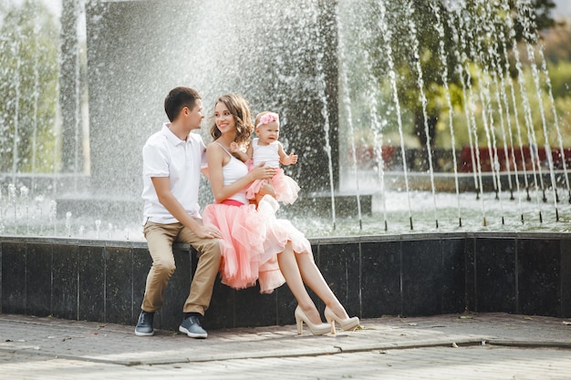 Jeune famille heureuse, assis près de la fontaine