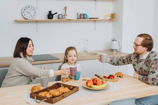 Jeune famille heureuse avec deux enfants prenant le petit déjeuner ensemble.