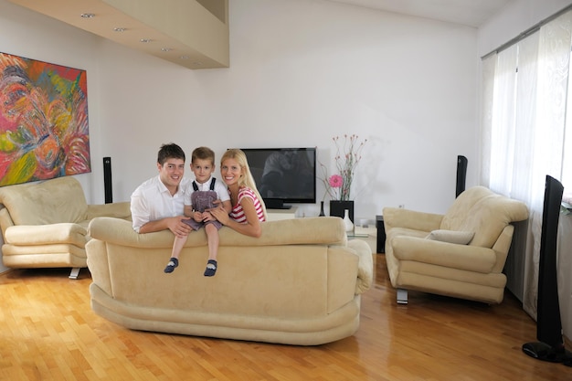 une jeune famille heureuse avec des enfants dans un salon moderne et lumineux s'amuse et regarde une grande télévision lcd à plat