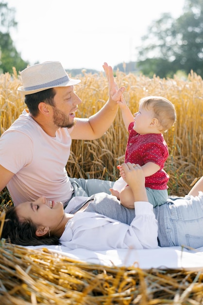 Une jeune famille heureuse avec un jeune fils s'amuse en été sur le terrain