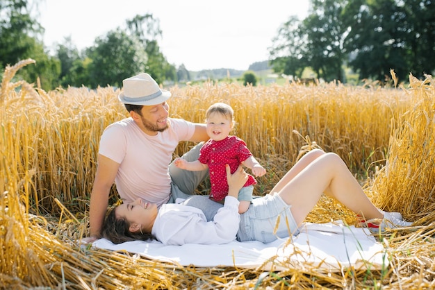 Une jeune famille heureuse avec un jeune fils s'amuse en été sur le terrain