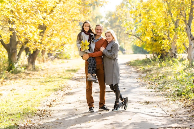 Jeune famille heureuse en marchant dans le parc en automne.