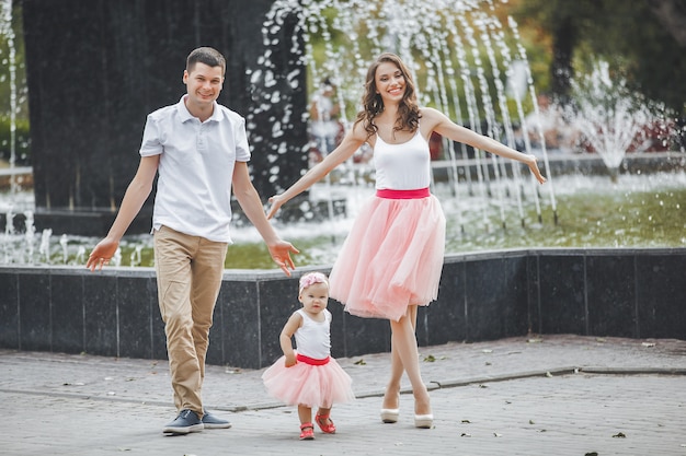 Jeune famille heureuse marchant près de la fontaine avec petite fille.