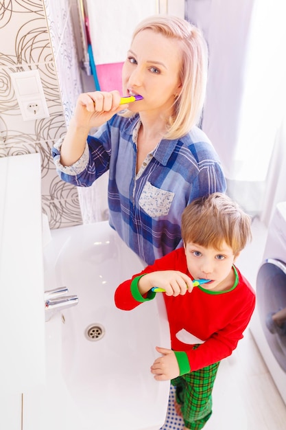 Jeune famille heureuse Mère et enfant petit garçon nettoie les dents avec une brosse à dents dans la salle de bain Maman et bébé en bonne santé