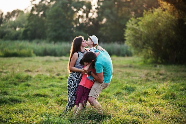 Jeune famille heureuse : mère, père, fils de deux enfants sur la nature s'amusant.