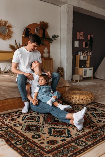 Une jeune famille heureuse passe du temps ensemble dans un intérieur de maison Une belle famille heureuse passe du temps ensemble à la maison Un jeune couple marié avec leur jolie fille La famille passe du temps à la maison