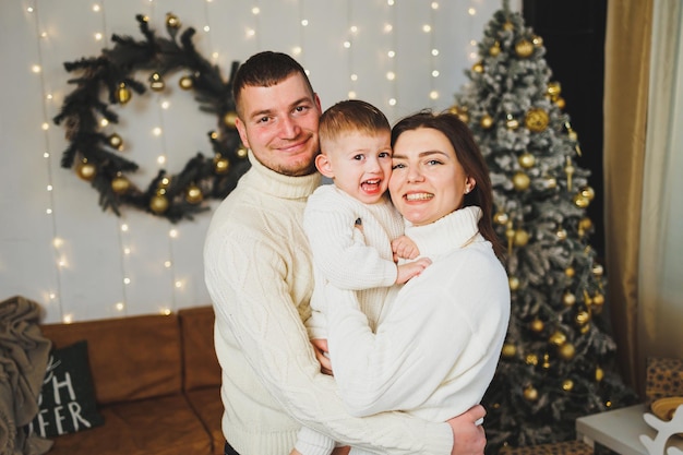 Une jeune famille heureuse avec un petit enfant célèbre le Nouvel An à la maison près du sapin de Noël Noël avec la famille Il est temps de célébrer le Nouvel An