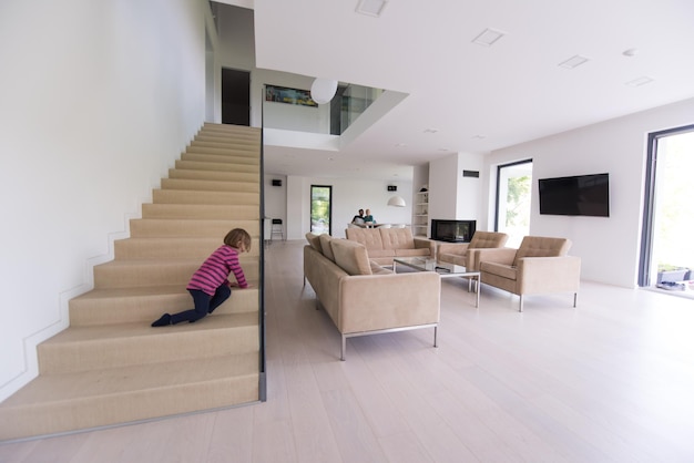 une jeune famille heureuse avec une petite fille s'amuse dans le salon moderne de leur villa de luxe