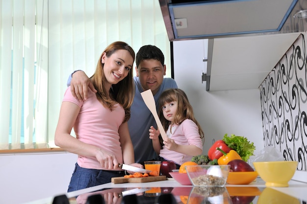 une jeune famille heureuse prend l'heure du déjeuner avec des fruits et des légumes frais dans une cuisine lumineuse