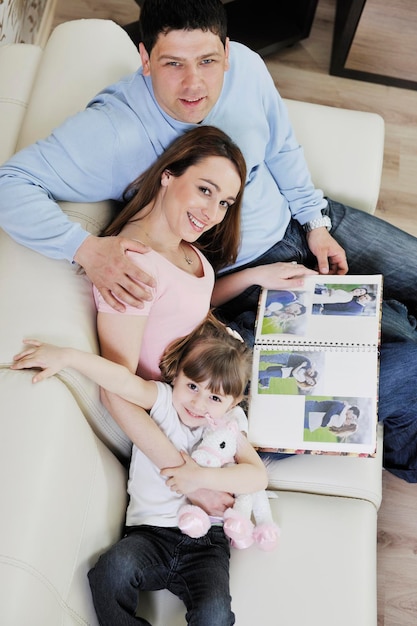 jeune famille heureuse regardant de vieilles photos dans un album photo à la maison