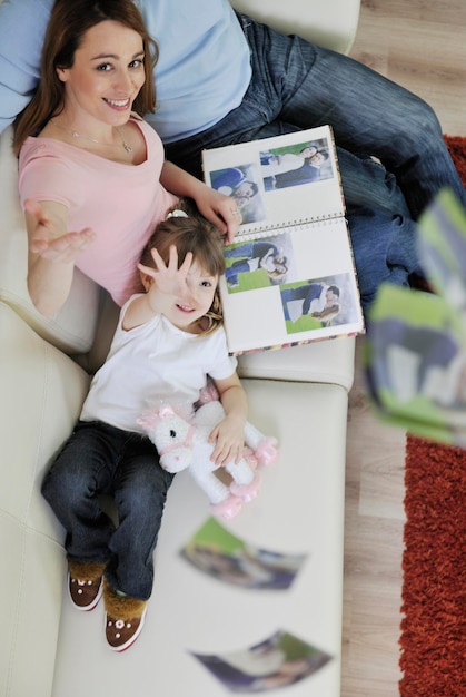 jeune famille heureuse regardant de vieilles photos dans un album photo à la maison