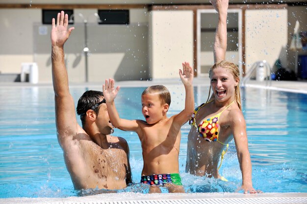 Une jeune famille heureuse s'amuse à la piscine.