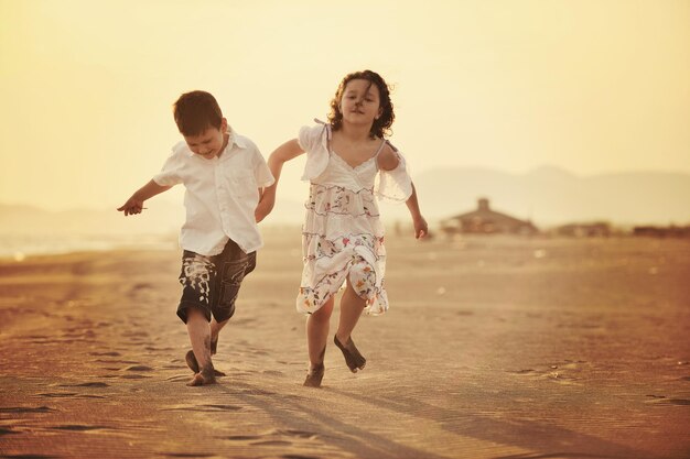 une jeune famille heureuse s'amuse sur la plage et saute au coucher du soleil