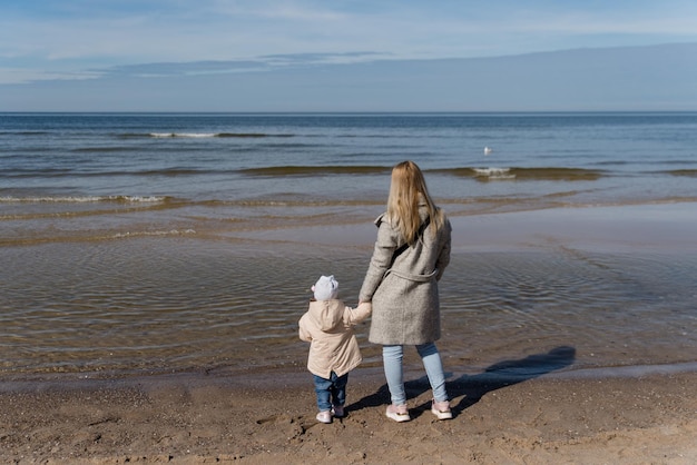 Une Jeune Famille Heureuse S'amuse Sur La Plage Et Saute Au Coucher Du Soleil