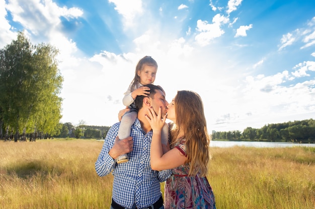 La jeune famille heureuse se promène dans la nature, au coucher du soleil