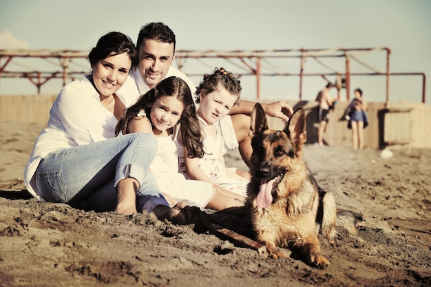 une jeune famille heureuse en vêtements blancs s'amuse et joue avec un beau chien en vacances sur une belle plage