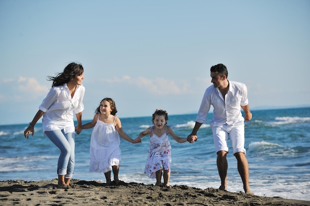 une jeune famille heureuse en vêtements blancs s'amuse en vacances sur une belle plage