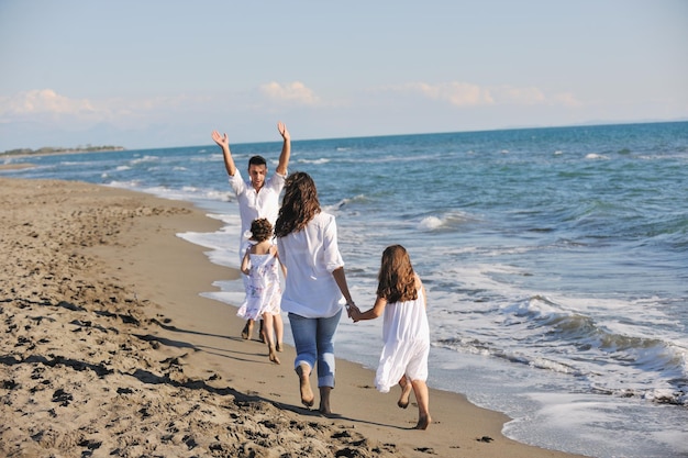 une jeune famille heureuse en vêtements blancs s'amuse en vacances sur une belle plage