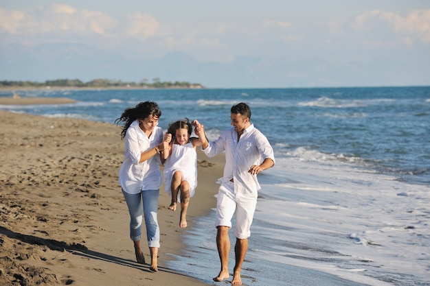 une jeune famille heureuse en vêtements blancs s'amuse en vacances sur une belle plage