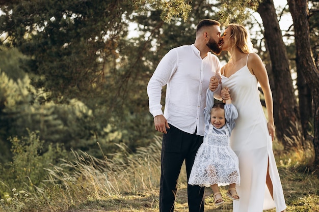 Jeune famille avec jolie fille marchant dans la forêt