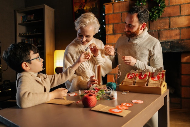 Jeune famille joyeuse faisant le calendrier de l'avent de noël ensemble assis à table sur fond de