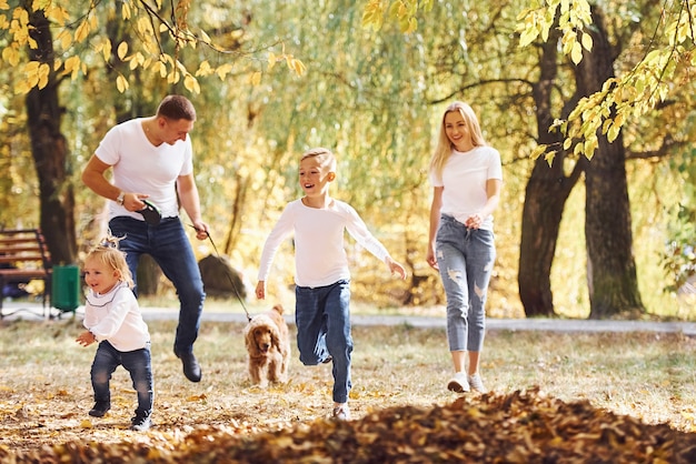 Une jeune famille joyeuse se promène ensemble dans un parc en automne.