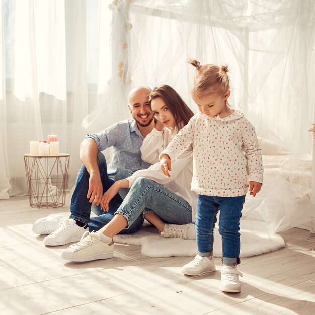 Jeune famille à la maison dans une chambre lumineuse avec leur fille