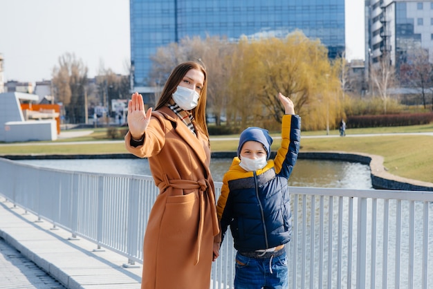 Une jeune famille marche et respire l'air frais par une journée ensoleillée pendant une quarantaine et une pandémie. Masques sur le visage des gens