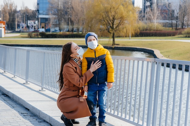 Une jeune famille marche et respire l'air frais par une journée ensoleillée pendant une quarantaine et une pandémie. Masques sur le visage des gens