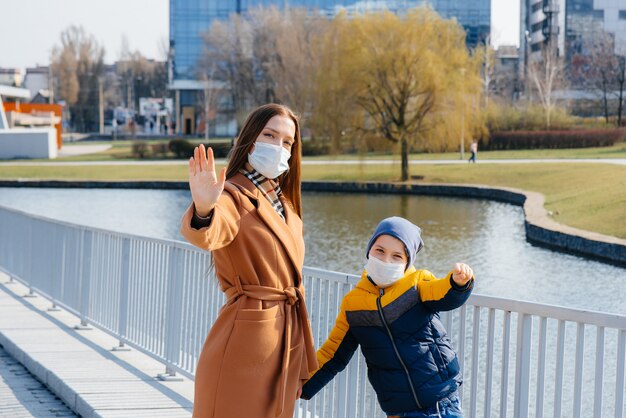 Une jeune famille marche et respire l'air frais par une journée ensoleillée pendant une quarantaine et une pandémie. Masques sur le visage des gens.