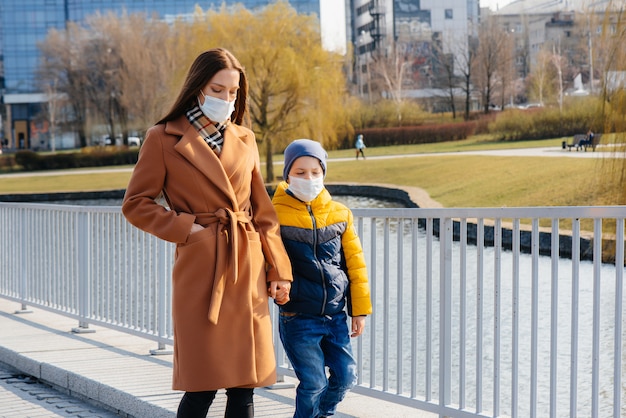 Une jeune famille marche et respire l'air frais par une journée ensoleillée pendant une quarantaine et une pandémie. Masques sur le visage des gens.