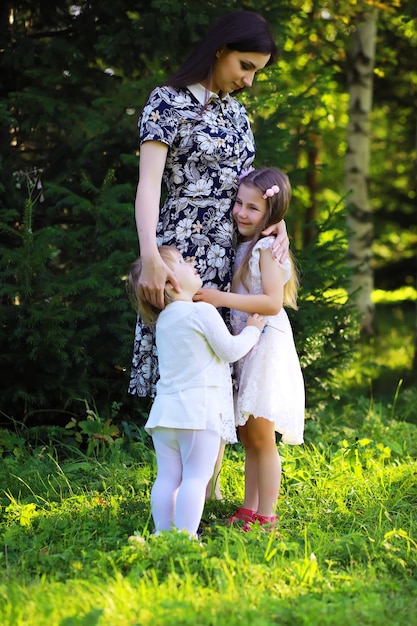 Jeune famille nombreuse lors d'une promenade matinale d'été. Belle mère avec enfants joue dans le parc.