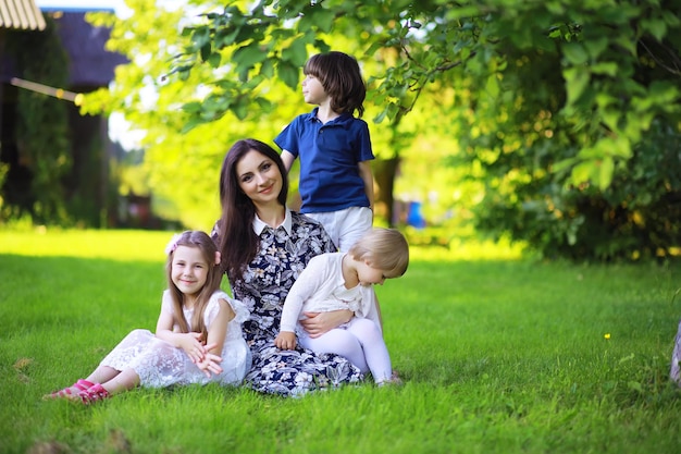 Jeune famille nombreuse lors d'une promenade matinale d'été. Belle mère avec enfants joue dans le parc.