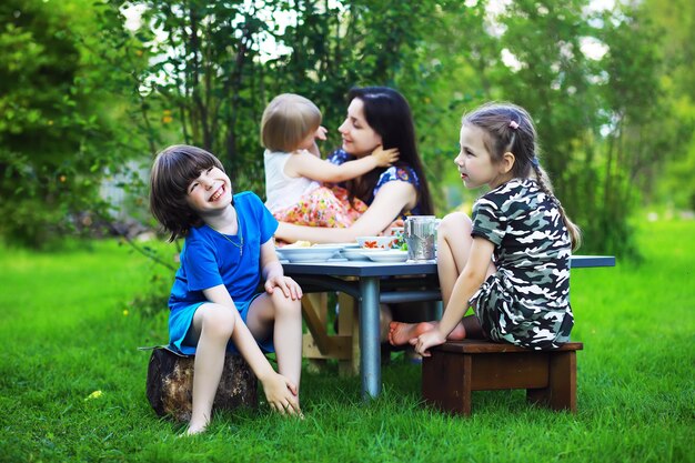 Une jeune famille nombreuse à un pique-nique un matin d'été. Une belle mère avec des enfants prend son petit déjeuner dans le parc.