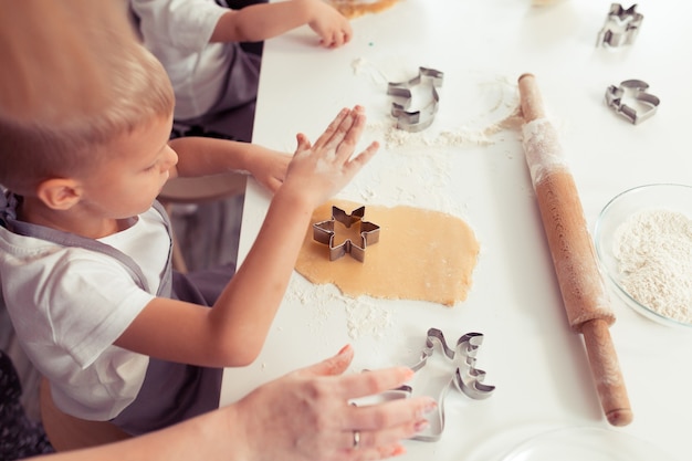 Jeune famille avec petit enfant et bébé fils faisant des biscuits au pain d'épice à la maison.