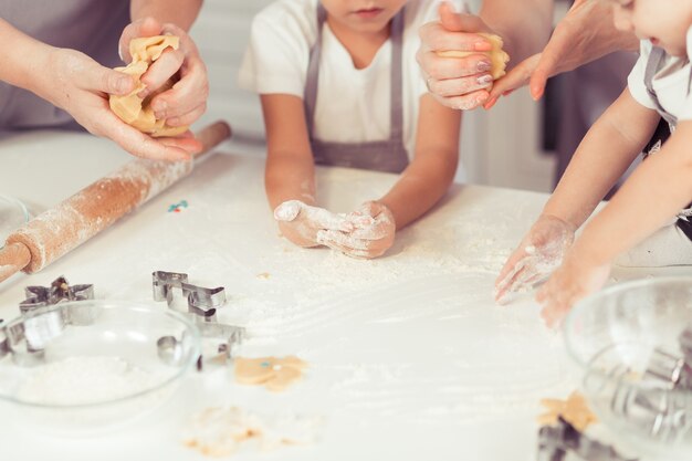 Jeune famille avec petit enfant et bébé fils faisant des biscuits au pain d'épice à la maison.